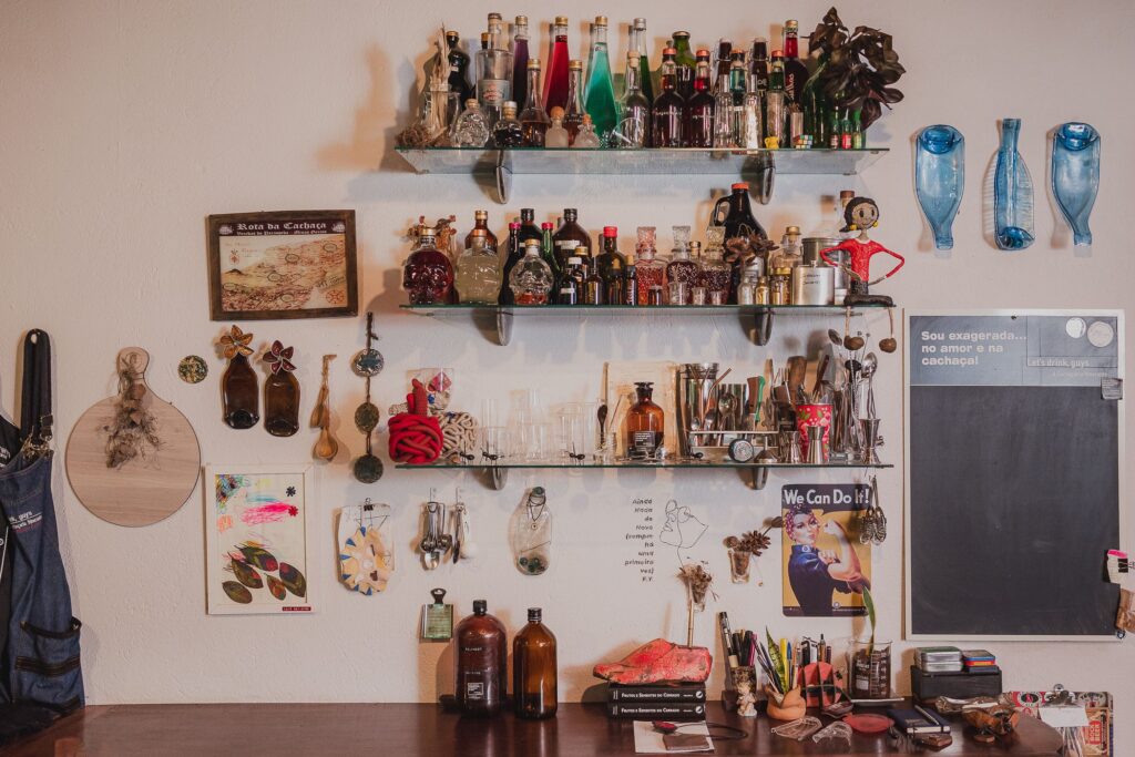 Ambiente interno do bistrô A Alquimista em Brumadinho, destacando prateleiras decoradas com garrafas e objetos que remetem à criatividade e à gastronomia molecular.
