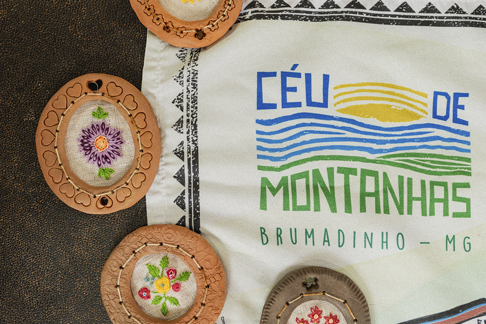 Logo do projeto Céu de Montanhas com peças de bordado artesanal, representando a identidade cultural de Brumadinho