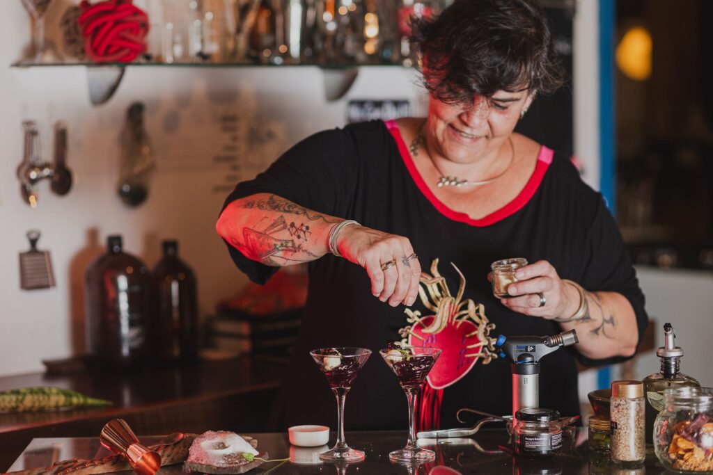 A chef mixologista Marcela Azevedo de A Alquimista, em Brumadinho, preparando um drinque inovador com técnicas de mixologia molecular.