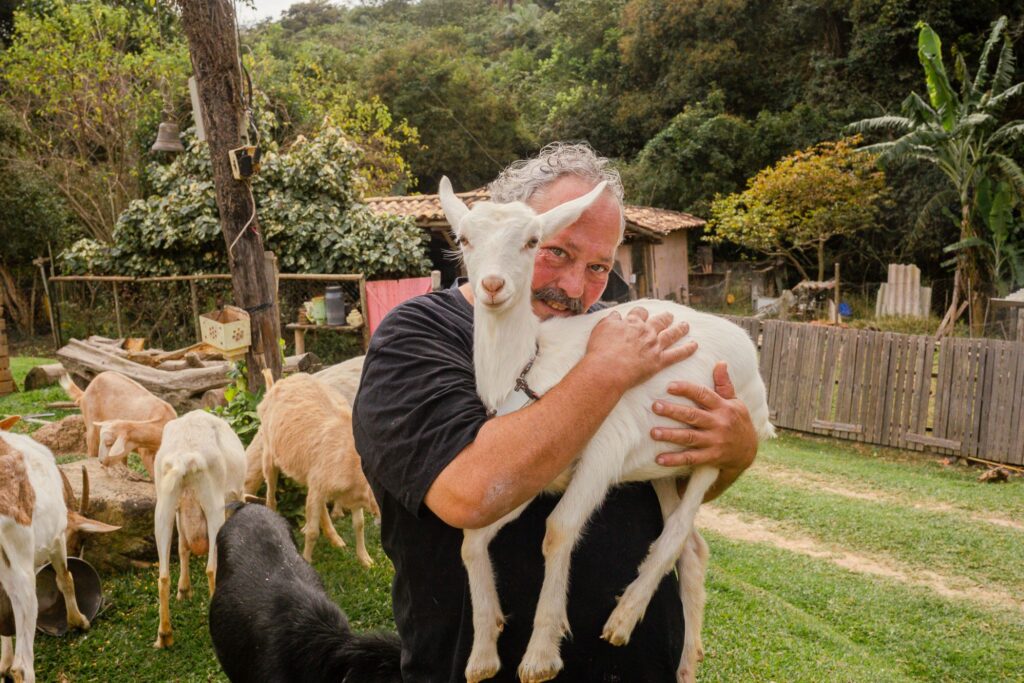 Ramon Fiuza, proprietário do Aprisco Chèvrèmon, acariciando uma cabra, ilustrando o cuidado e afeto com os animais na propriedade em Brumadinho.