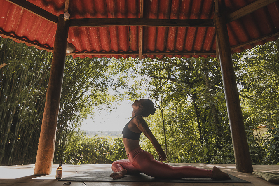 Mulher praticando yoga em espaço ao ar livre cercado pela natureza em Brumadinho, durante vivência do projeto Céu de Montanhas