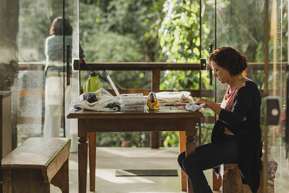 Mulher bordando em uma mesa no Bordadeiras da Serra da Moeda, um empreendimento do Céu de Montanhas em Brumadinho.