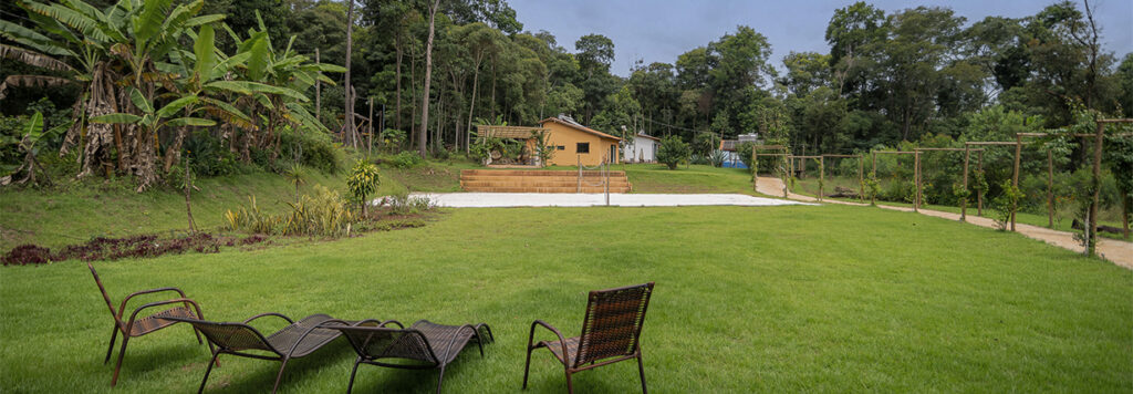 Quintal gramado, rodeado por mata verde, na Ecovila Coração da Mata